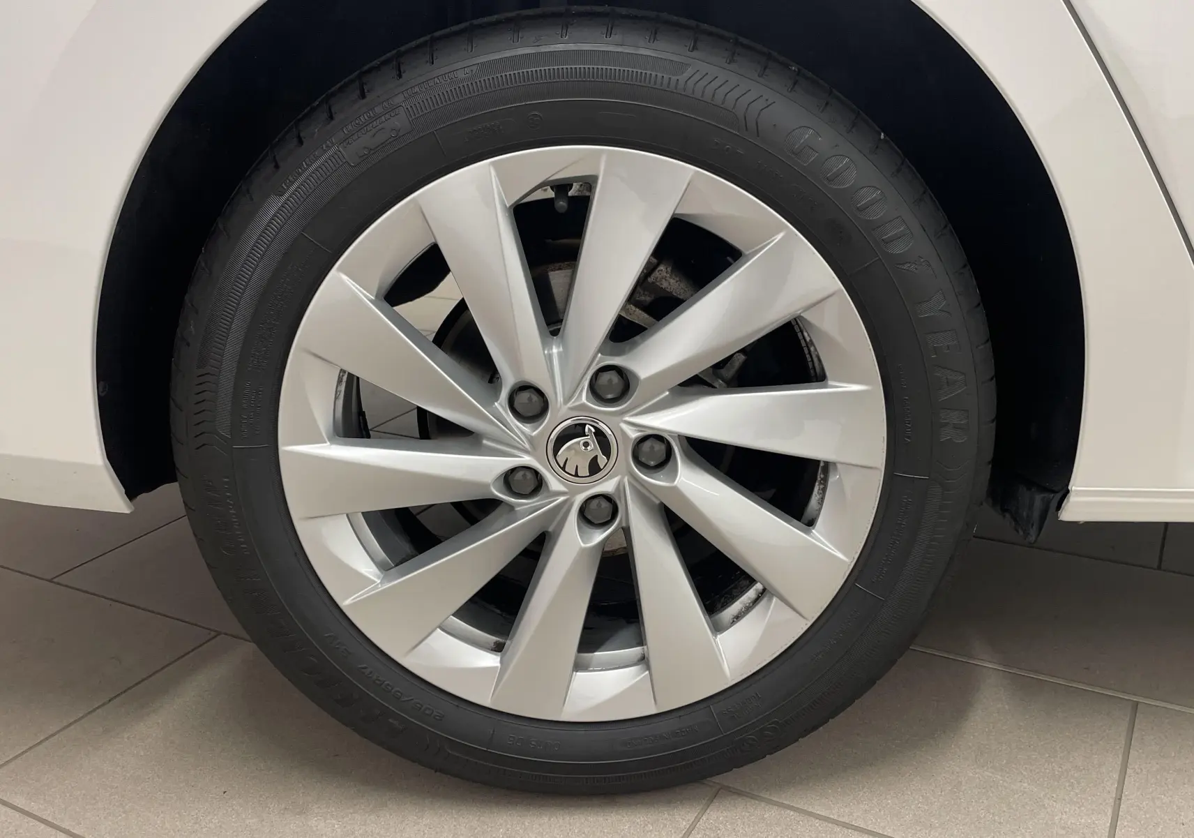 Gros plan sur la roue avant droite blanche d'une Skoda Octavia 2024 avec jante argentée et pneu Goodyear.