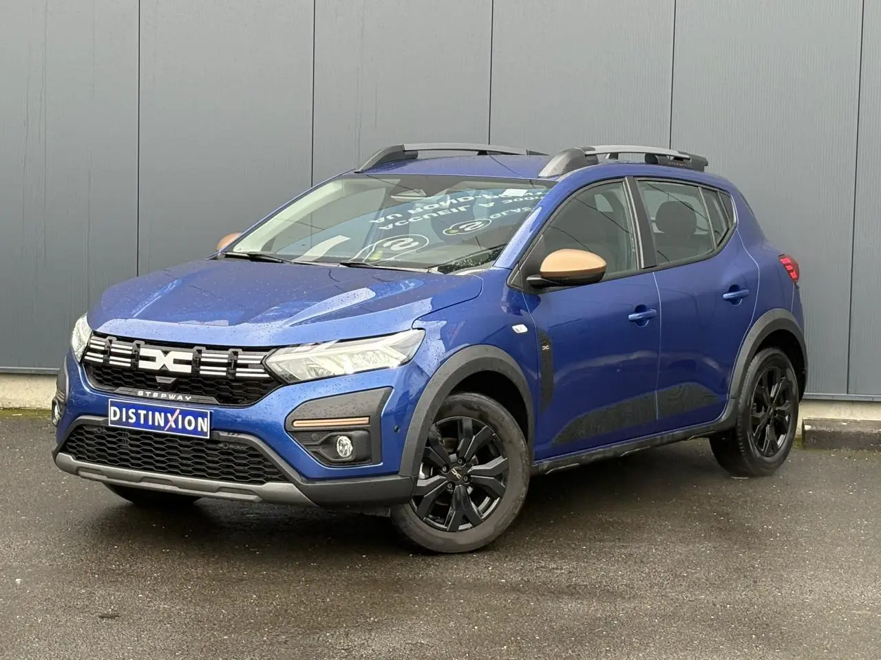 Dacia Sandero Stepway Bleu Iron en 3/4 avant droit avec jantes noires et coques de rétroviseurs cuivrées.