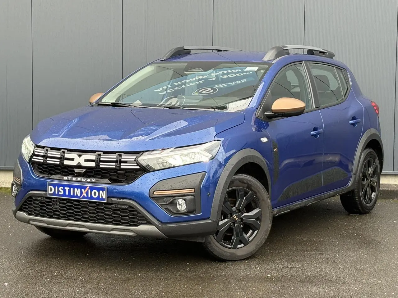 Dacia Sandero Stepway Bleu Iron en 3/4 avant droit avec jantes noires et coques de rétroviseurs cuivrées.