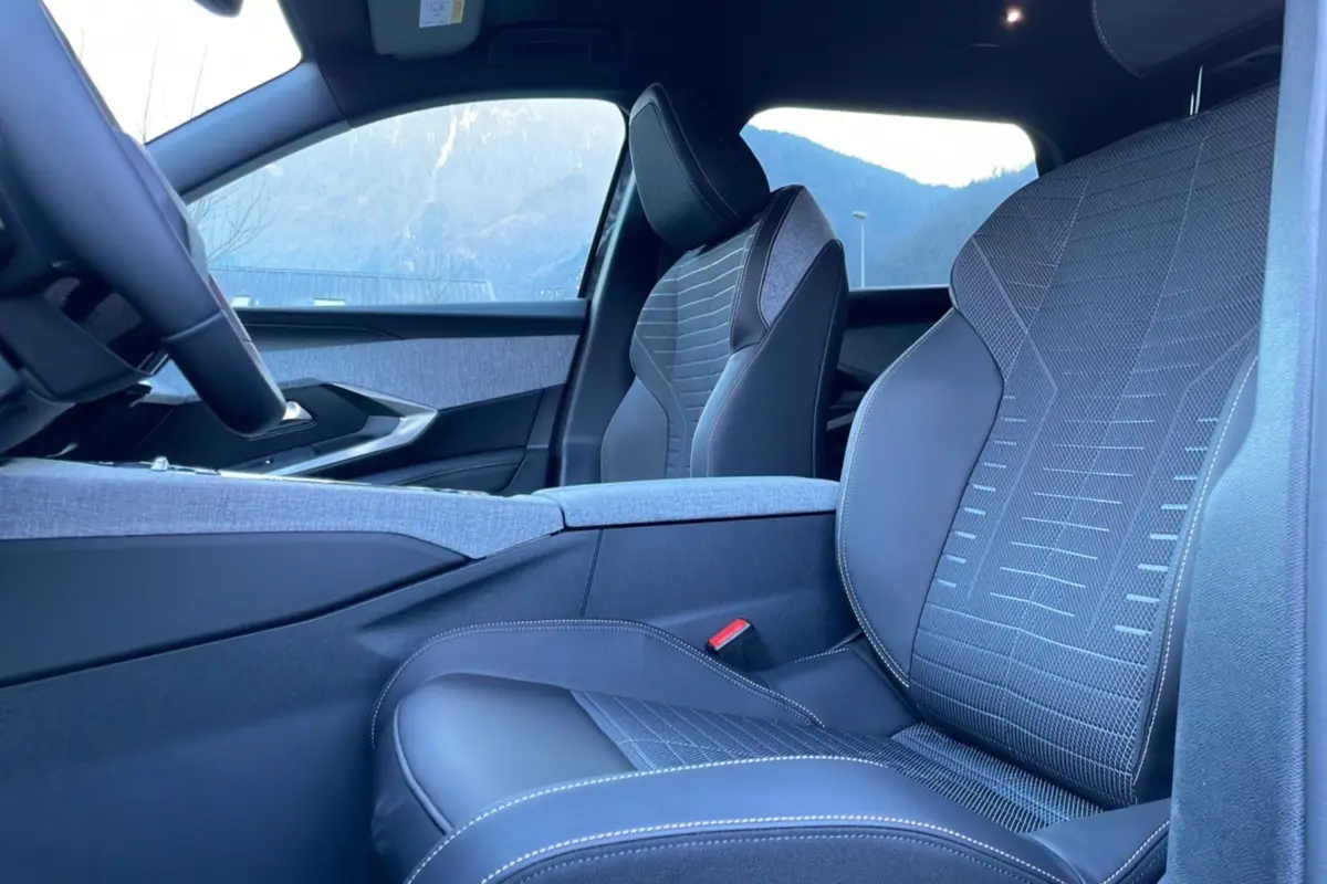 Vue intérieure côté droit montrant les sièges avant en cuir tissu gris avec surpiqûres contrastées du Peugeot 5008 Hybrid 2025.
