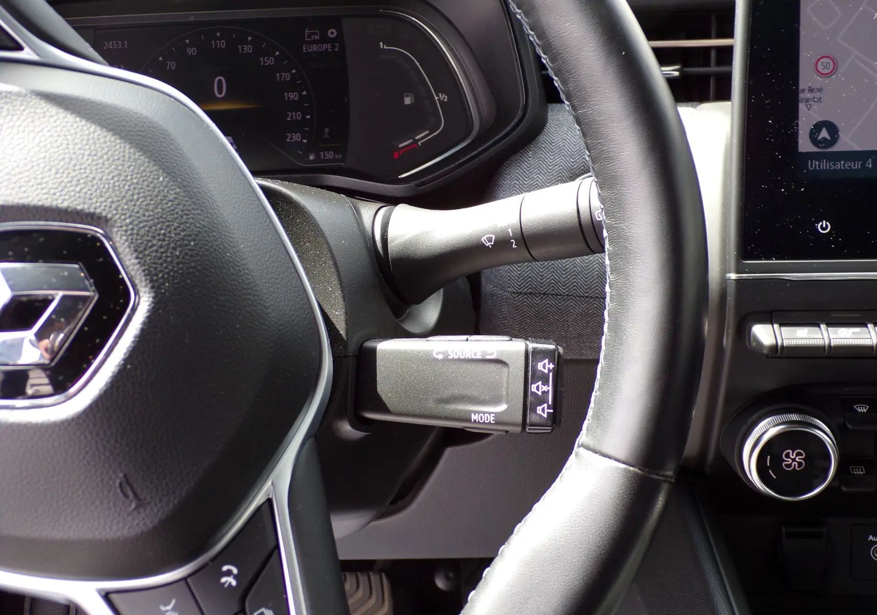 Vue rapprochée du volant noir de la Renault Clio V 1.3 TCE 140 ch avec commandes et tableau de bord numérique.