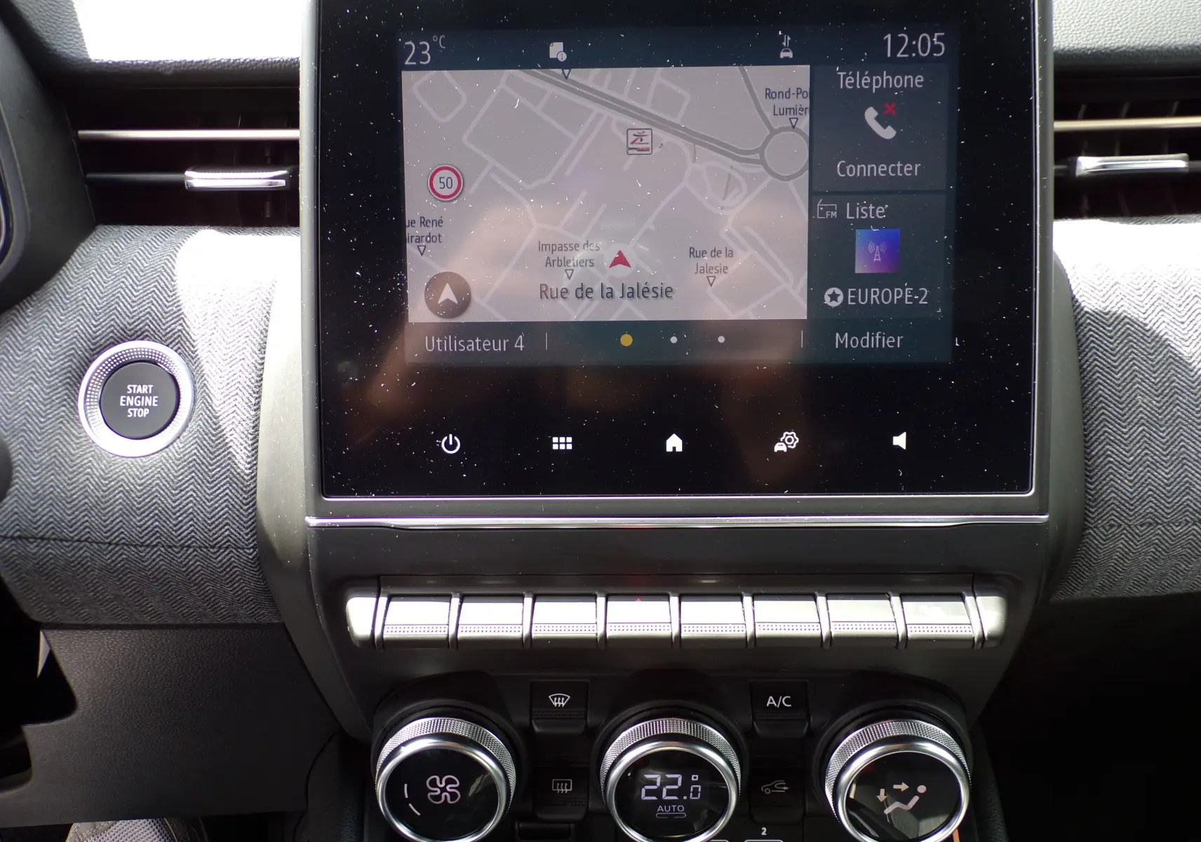 Tableau de bord de Renault Clio V blanc 2022, vue centrée sur l'écran tactile et les commandes de climatisation.