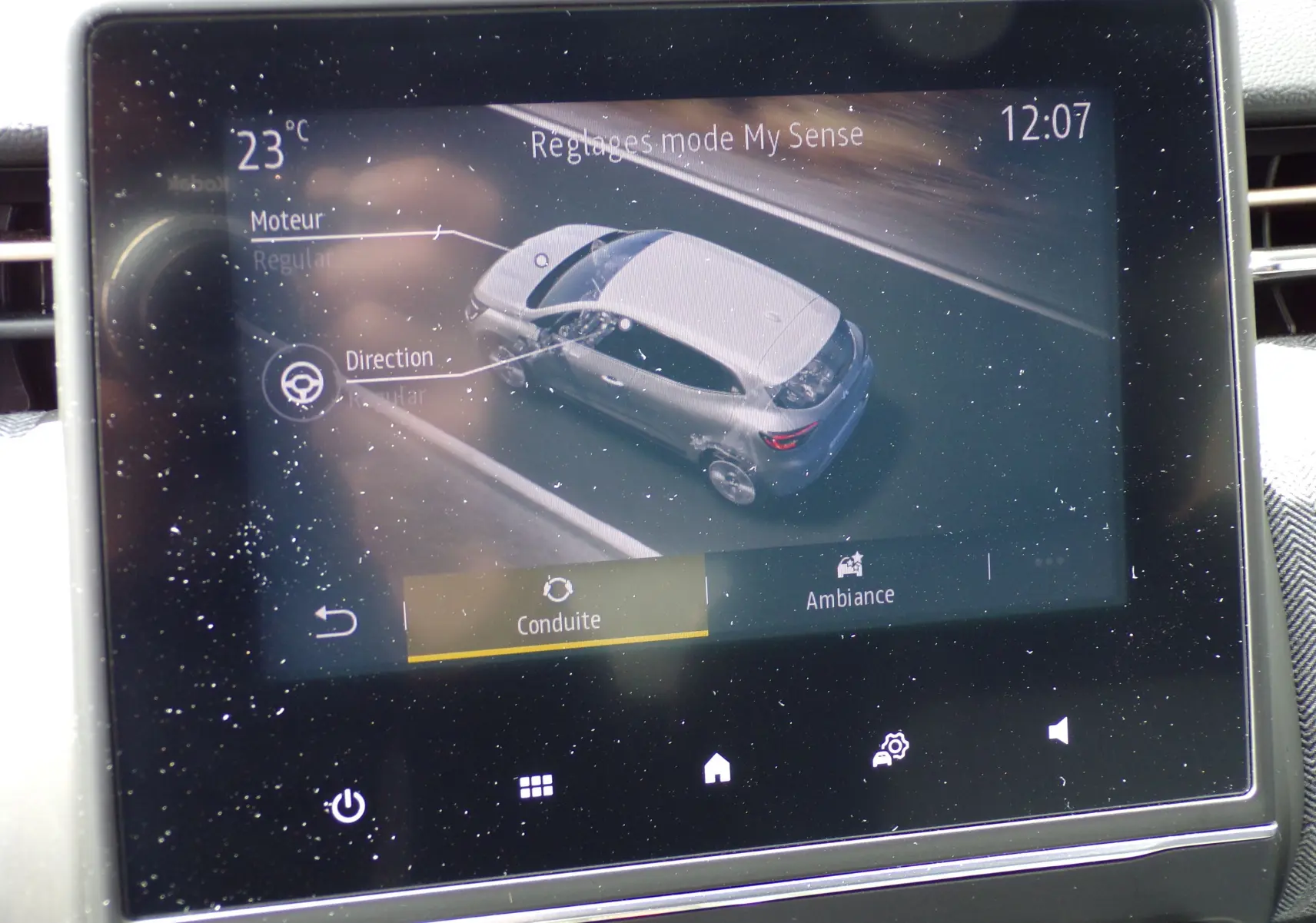 Écran tactile intérieur montrant la configuration de conduite d'une Renault Clio V blanche, vue en 3D sur l'interface.