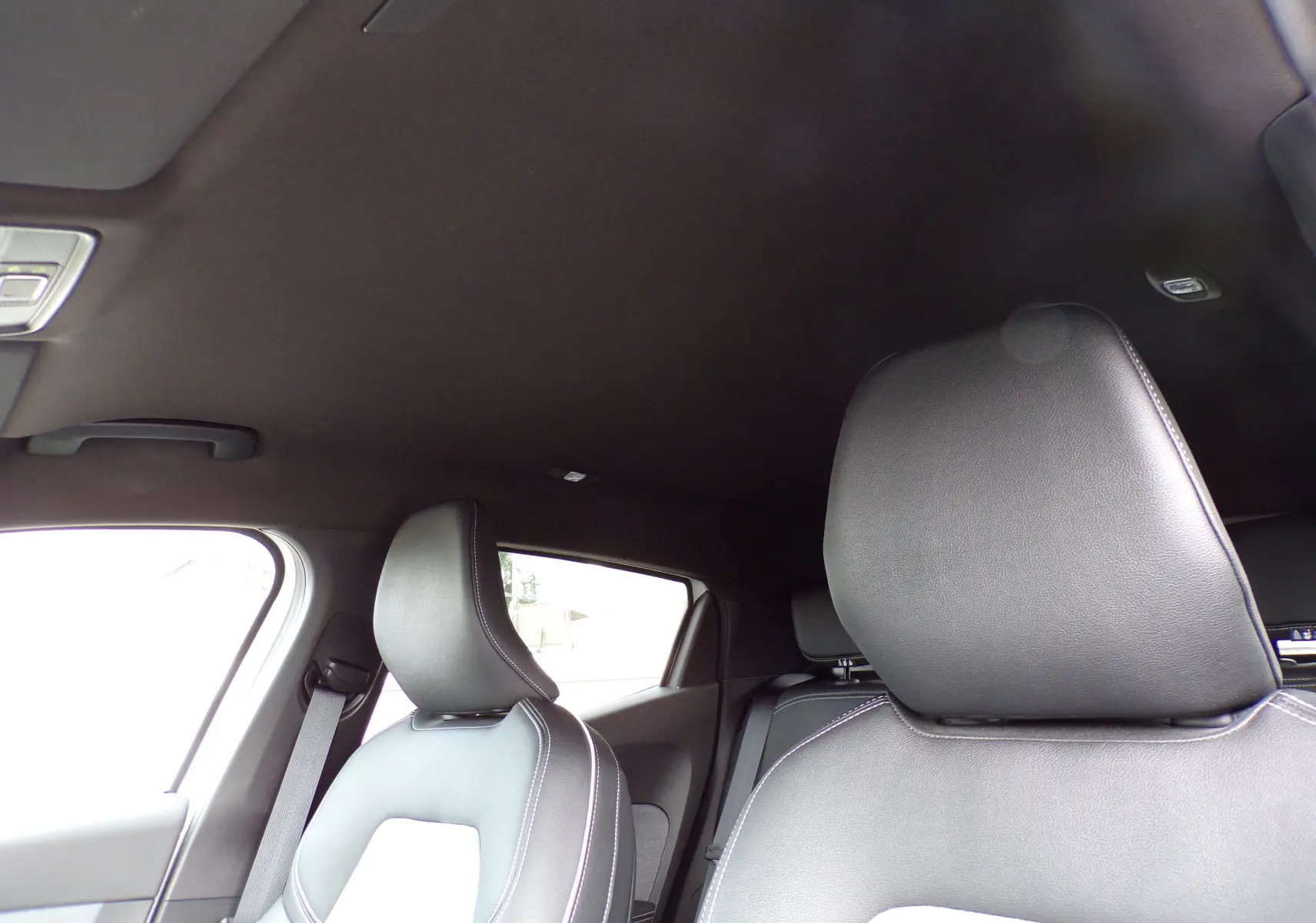 Vue intérieure sur les sièges avant en cuir noir avec surpiqûres blanches d'une Renault Clio V blanche de 2022.