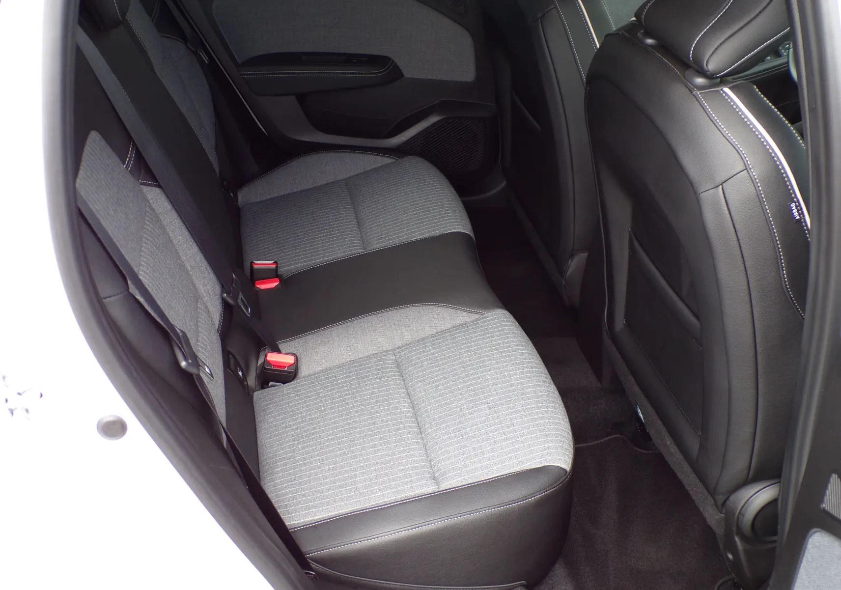 Vue intérieure côté gauche des sièges arrière gris et noirs de la Renault Clio V blanche de 2022.