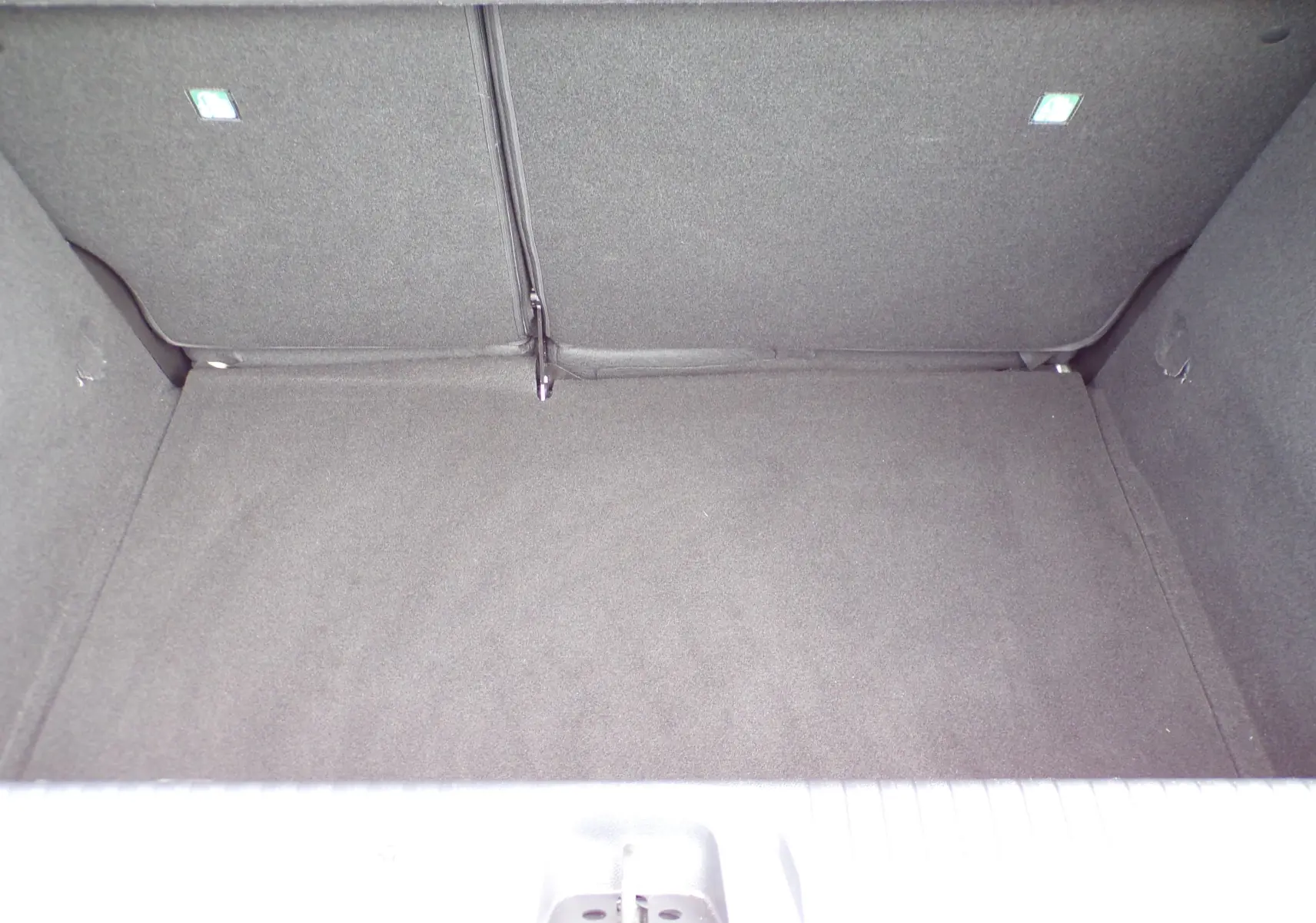 Coffre vide de la Renault Clio V blanche, vue plongeante sur l'espace de chargement intérieur.