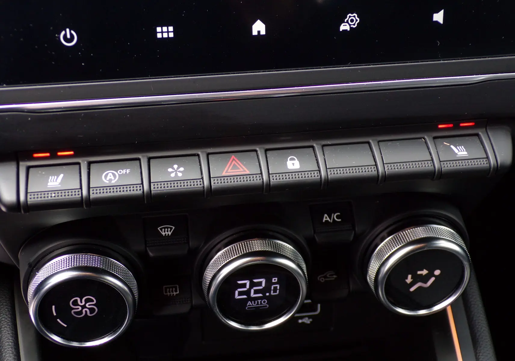 Gros plan sur la console centrale de la Renault Clio V blanche, montrant les commandes de climatisation et les boutons de fonction.