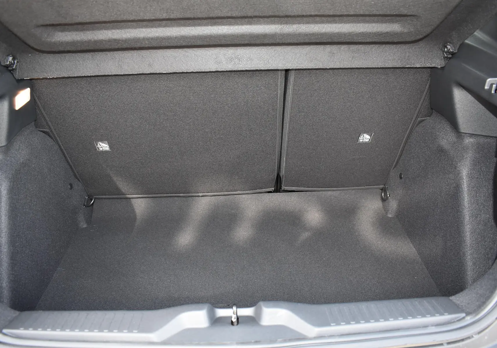 Coffre ouvert d'une Citroën C3 2025 bleu toit noir, vue intérieure montrant l'espace de rangement vide et les sièges arrière rabattables.