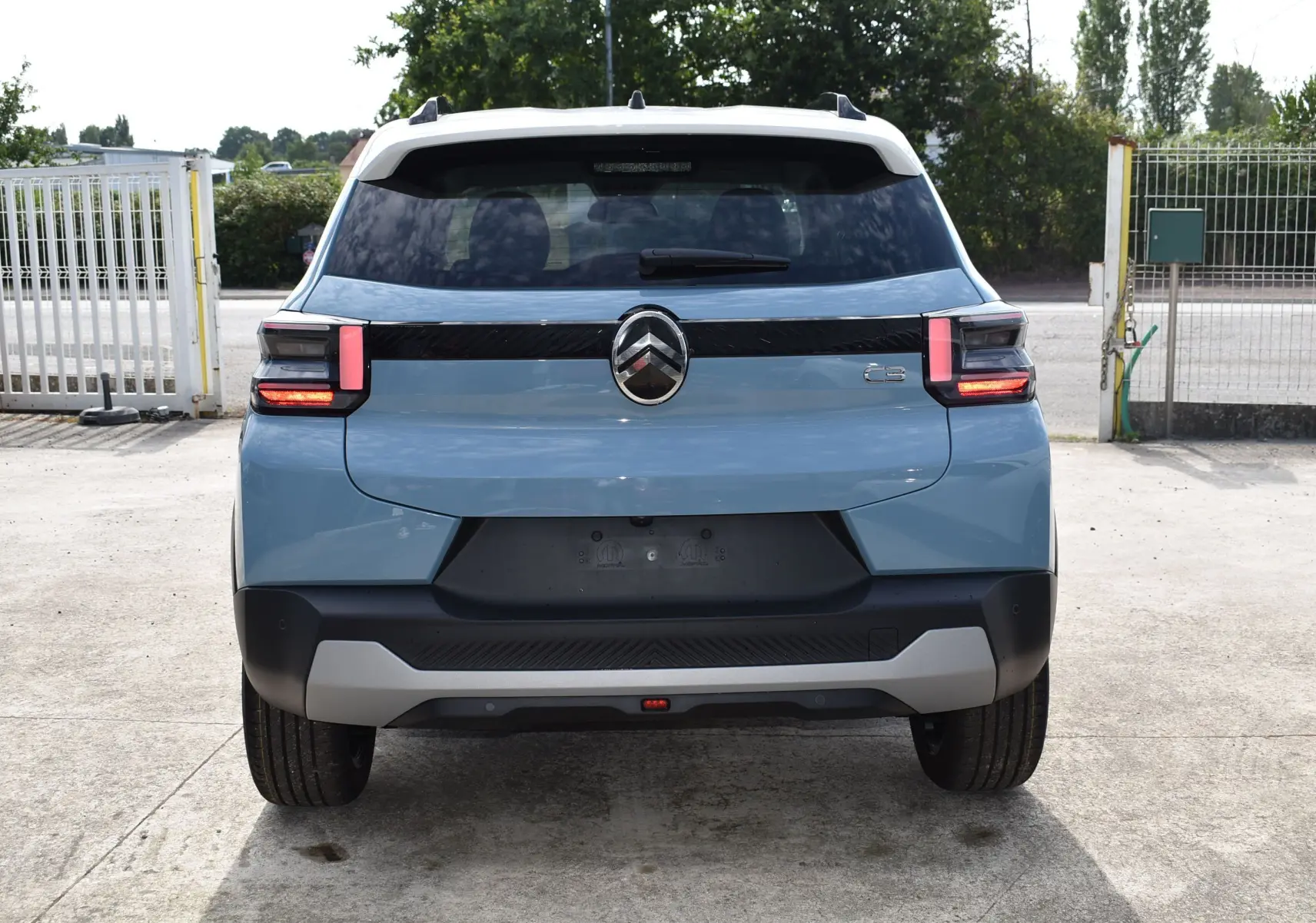 Vue arrière d'une Citroën C3 2025 bleu avec toit noir, feux arrière LED et logo chevrons central bien visible.