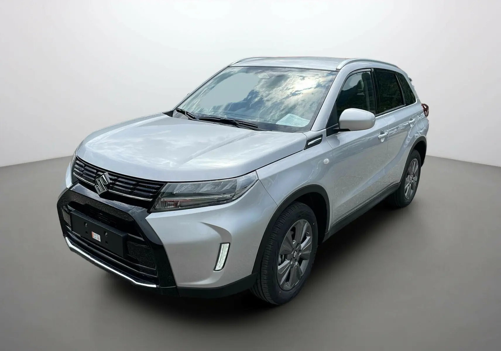 Suzuki Vitara 2025 Silky Silver vue 3/4 avant droit avec calandre noire et feux LED distinctifs.