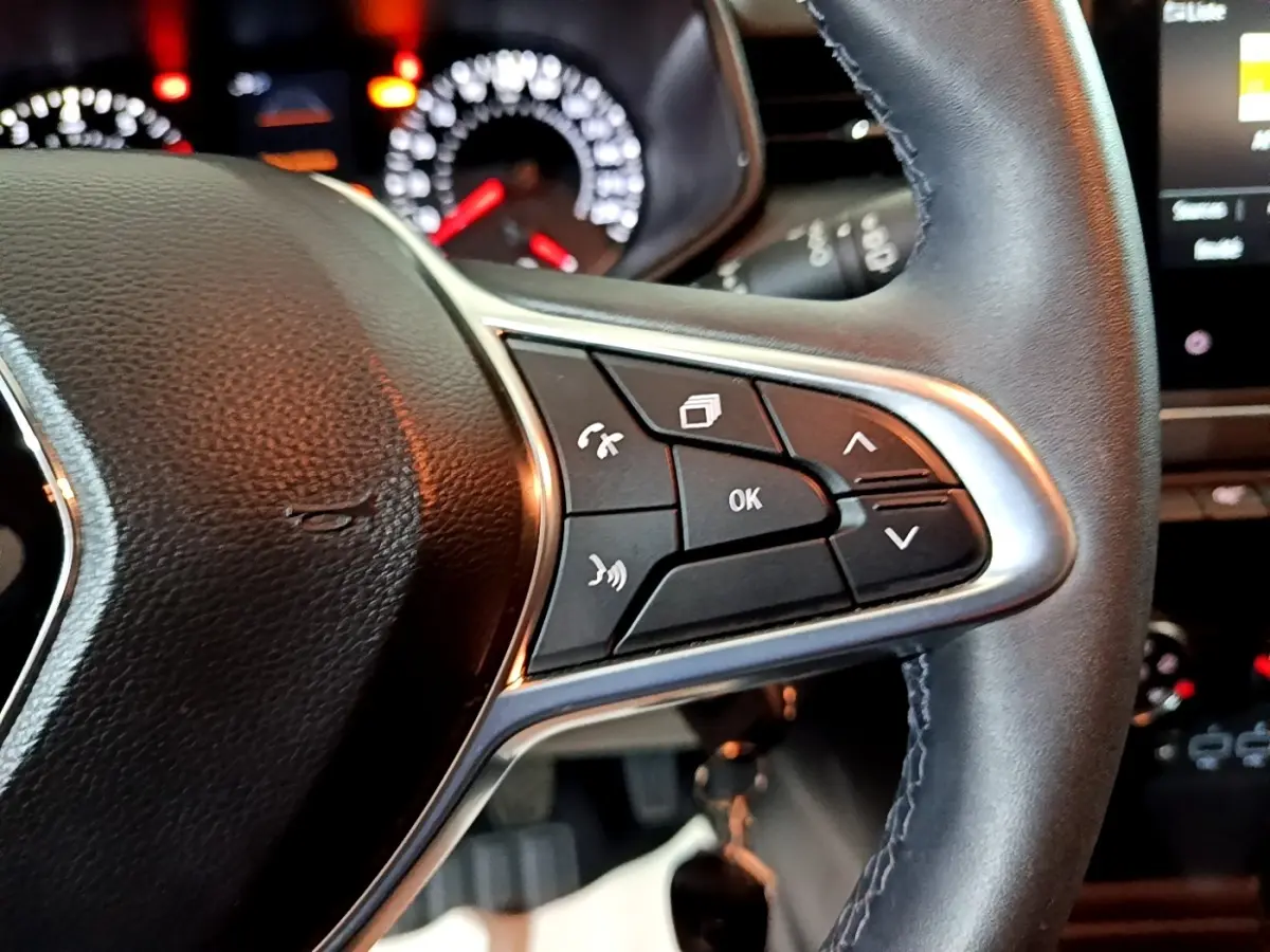 Gros plan sur le volant cuir noir côté gauche de la Renault Clio 2023 avec commandes multifonctions et tableau de bord lumineux.