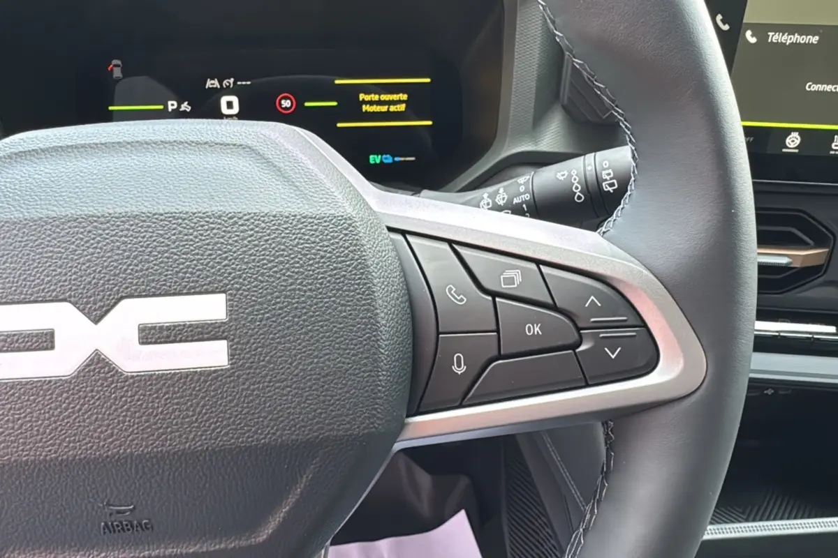 Gros plan sur le volant cuir noir du Dacia Bigster Hybrid 155 Extreme Plus avec commandes multifonctions et tableau de bord digital.