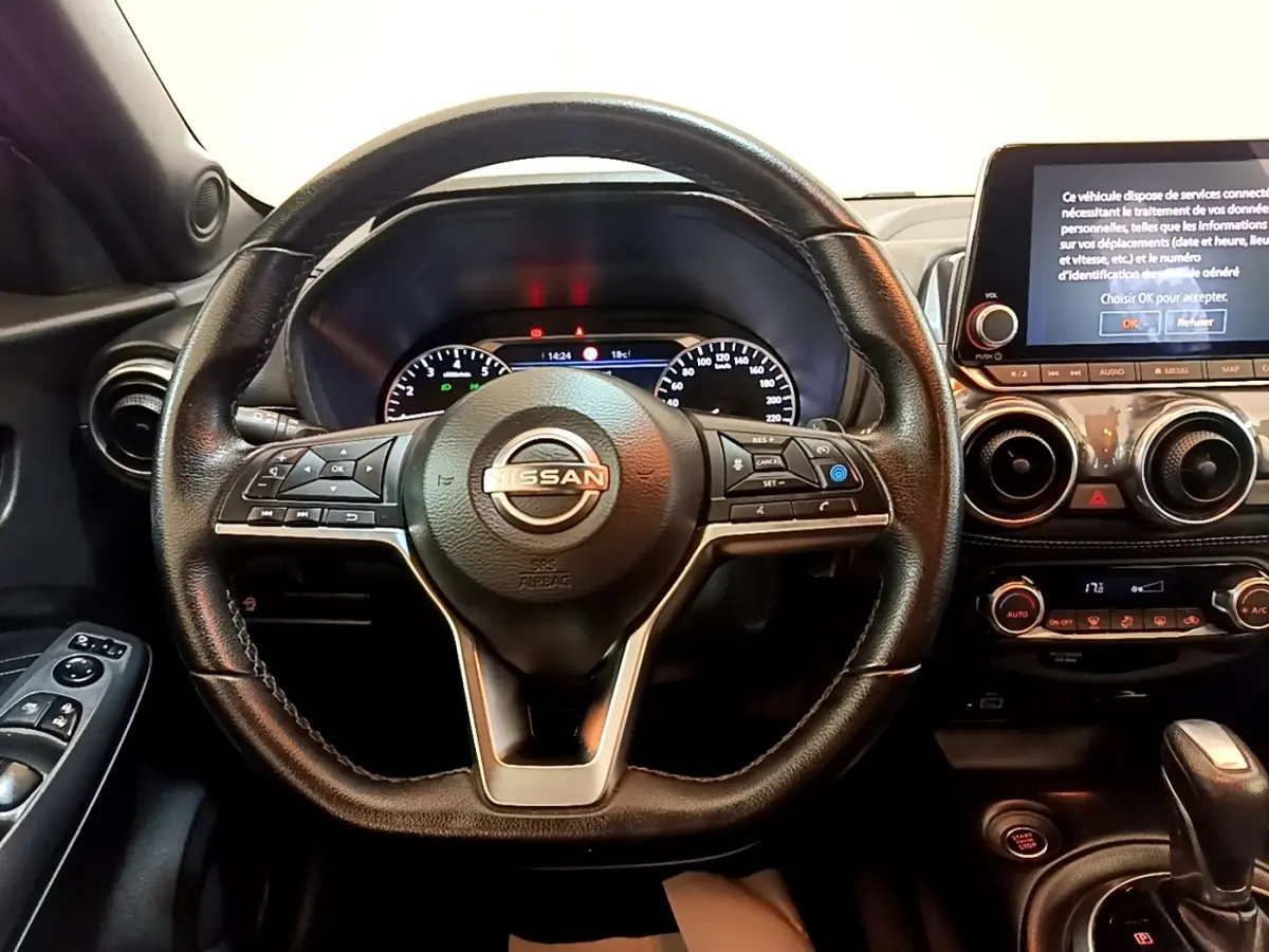 Vue intérieure centrée sur le volant Nissan Juke noir 2022 avec tableau de bord digital et écran tactile.