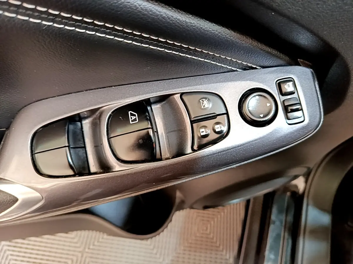 Gros plan sur la commande des vitres et rétroviseurs côté conducteur du Nissan Juke noir 2022.