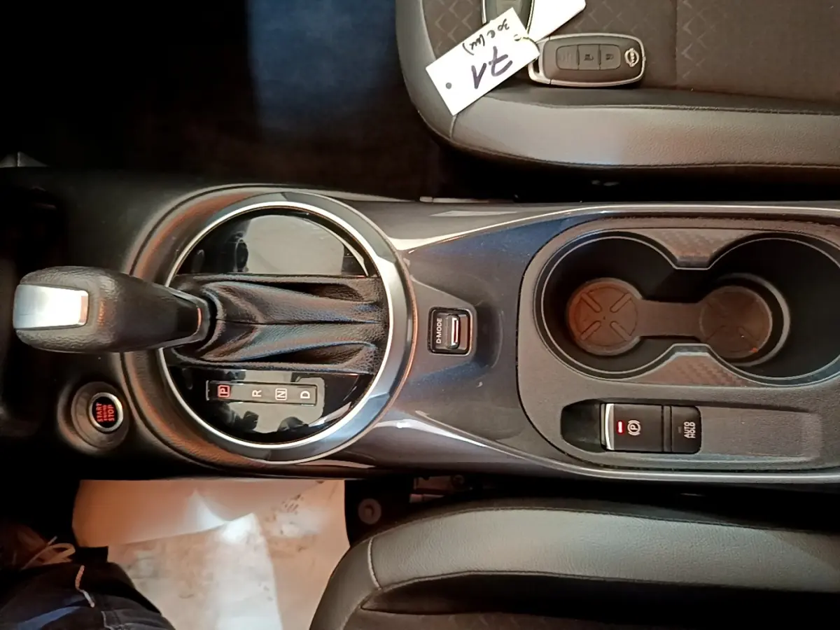 Vue plongeante sur la console centrale noire du Nissan Juke 2022, avec levier de boîte auto et porte-gobelets.