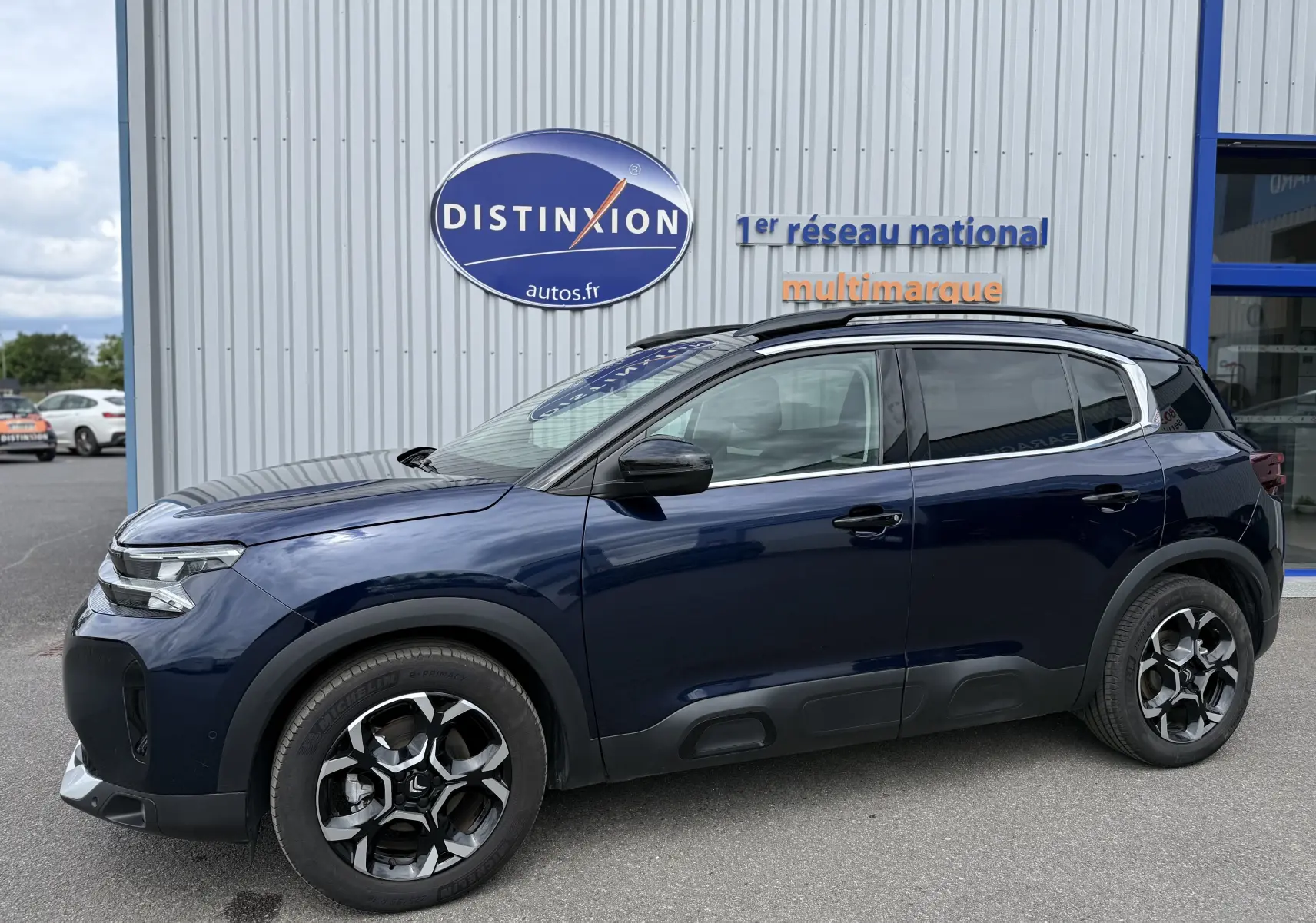 Vue de profil côté gauche d’un Citroën C5 Aircross Hybrid 145 bleu foncé avec jantes bi-ton et protections noires sur les bas de caisse.