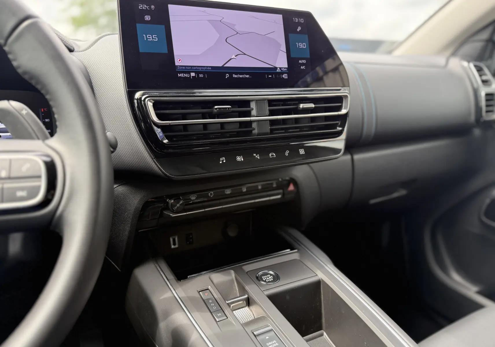 Vue intérieure côté conducteur du tableau de bord et console centrale du Citroën C5 Aircross Hybrid bleu foncé avec écran tactile et commandes modernes.