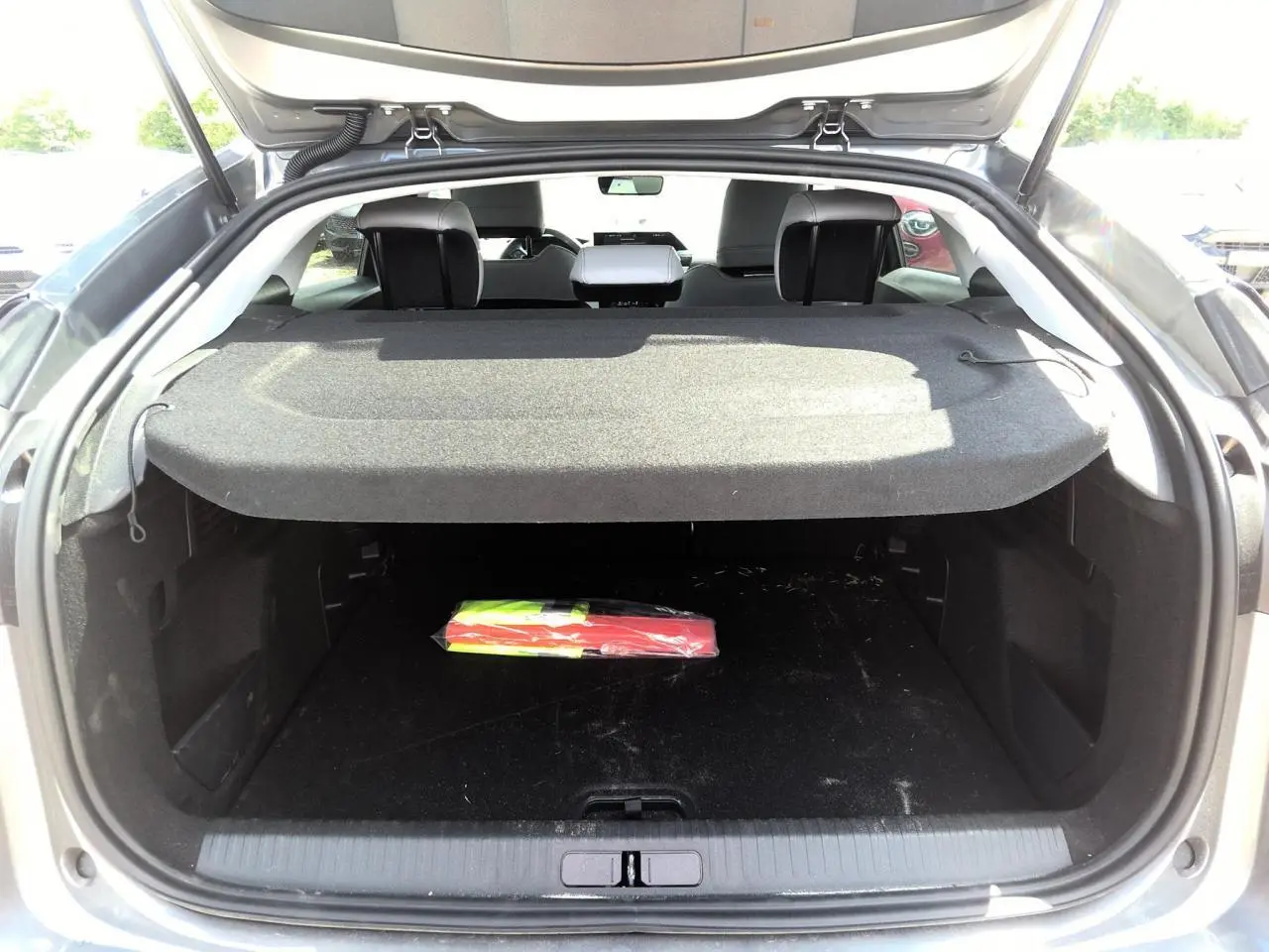 Coffre ouvert d'une Citroën C4 gris Mercury, vue arrière montrant l'espace de chargement avec cache-bagages déployé.
