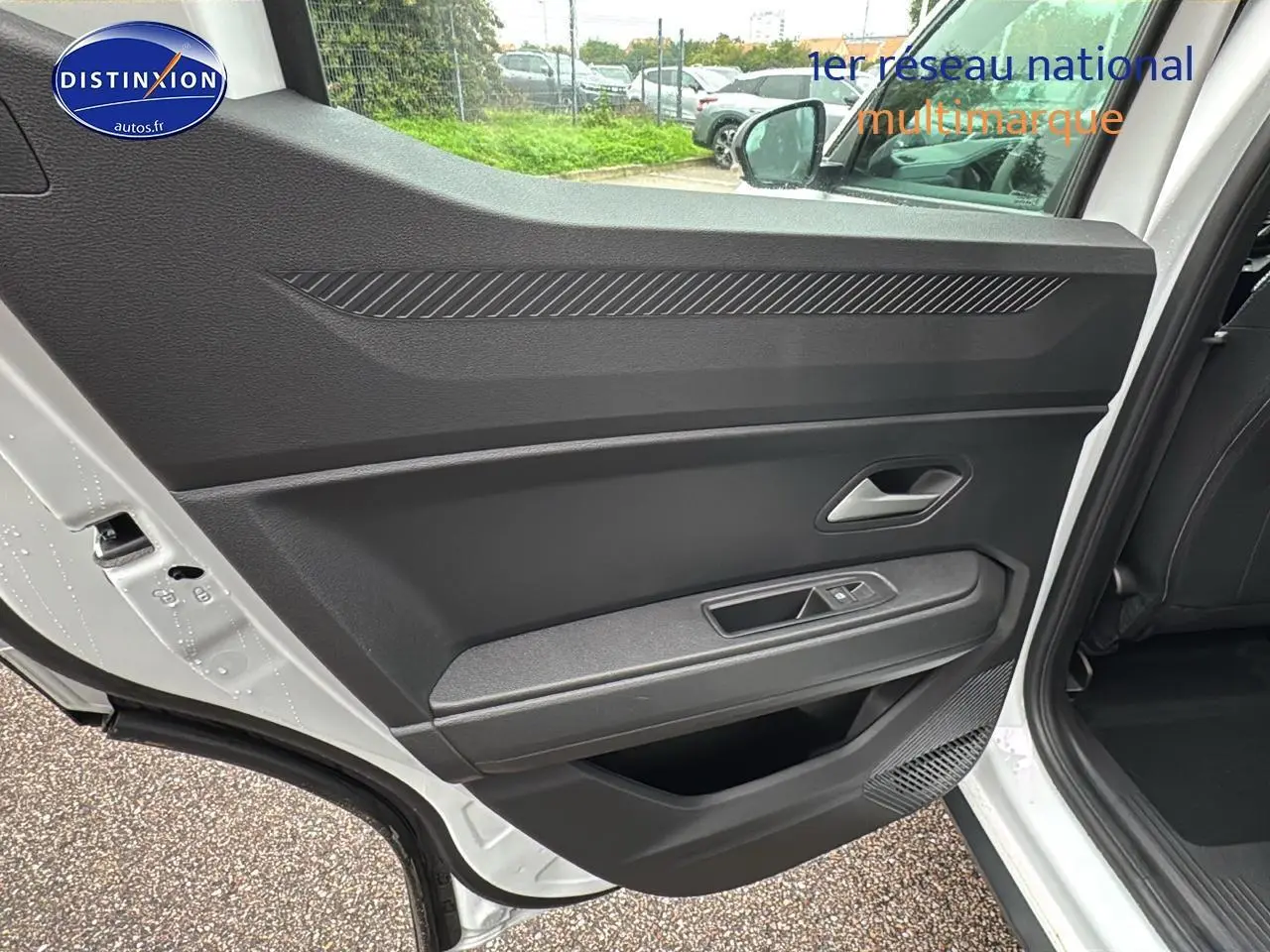 Vue intérieure de la porte arrière gauche blanche arctic du Dacia Duster 2025 avec commandes de vitre et rangement intégré.