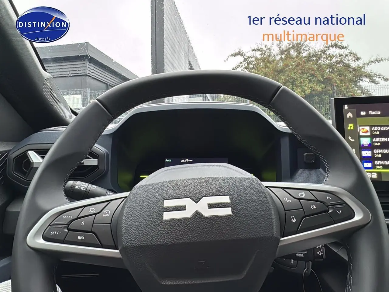 Vue intérieure centrée sur le volant multifonction noir du Dacia Duster 2025 avec tableau de bord et écran tactile visibles.