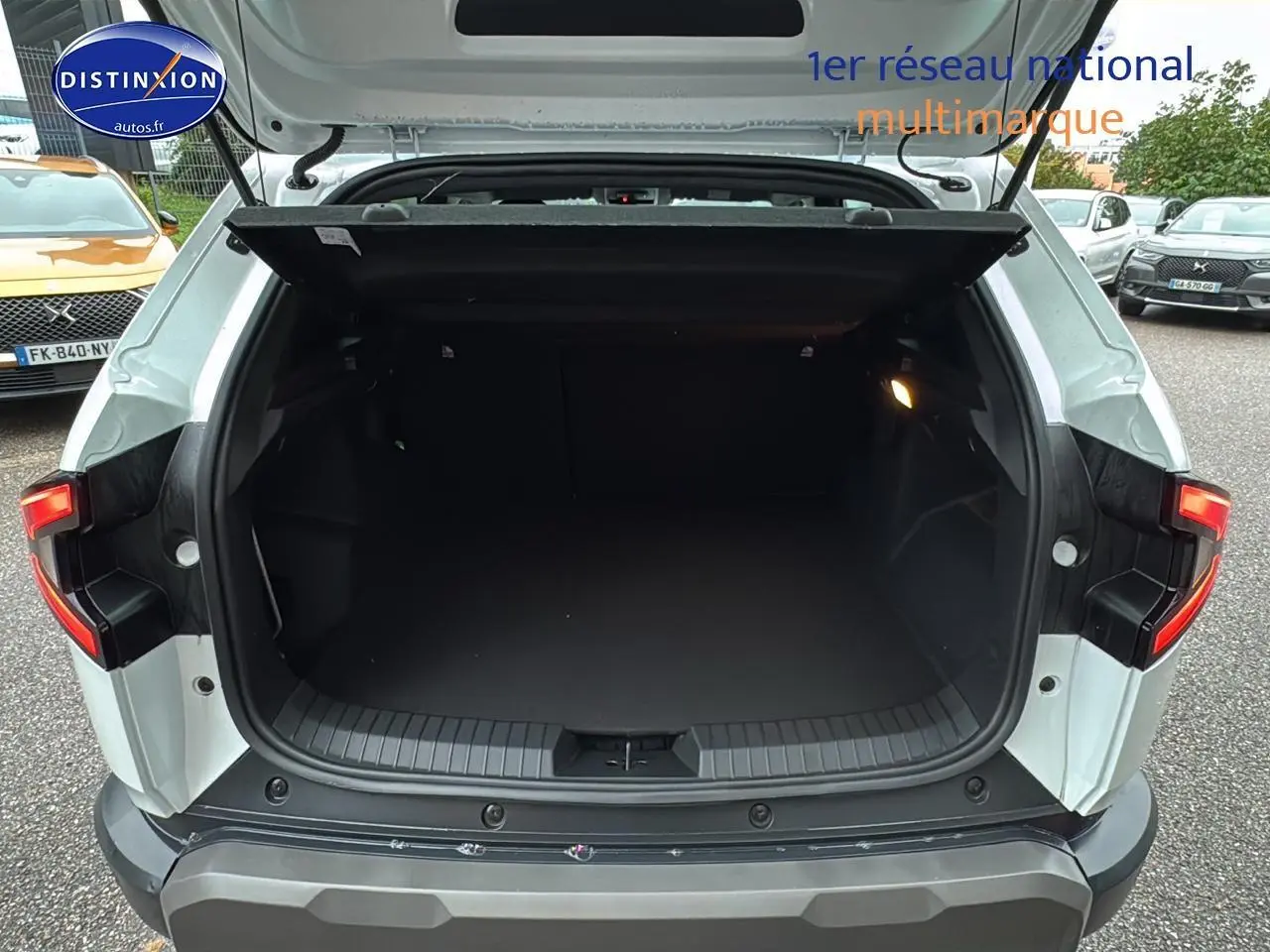 Coffre ouvert vu de l'arrière d'un Dacia Duster blanc Arctic 2025 avec feux arrière LED allumés.