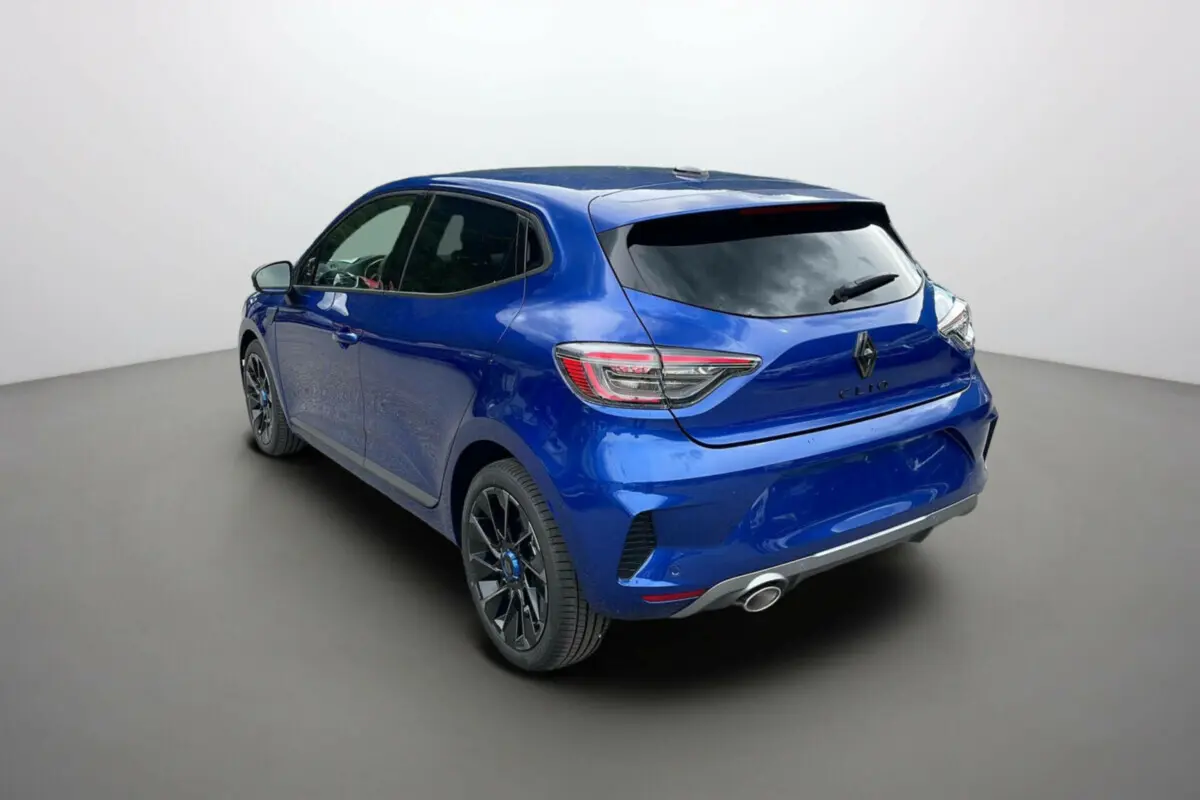 Vue 3/4 arrière droite d'une Renault Clio V E-TECH 145 Esprit Alpine bleu iron avec jantes noires et échappement visible.