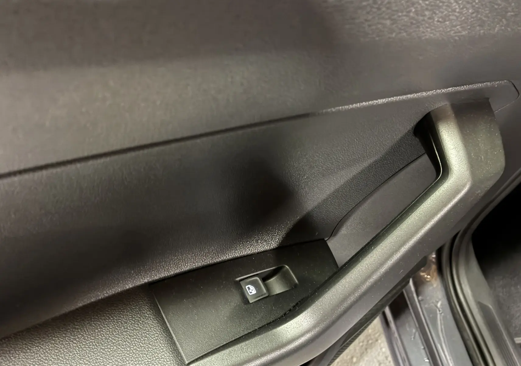 Poignée intérieure et bouton de commande de vitre électrique sur la porte côté droit d'une Volkswagen Polo grise 2025.