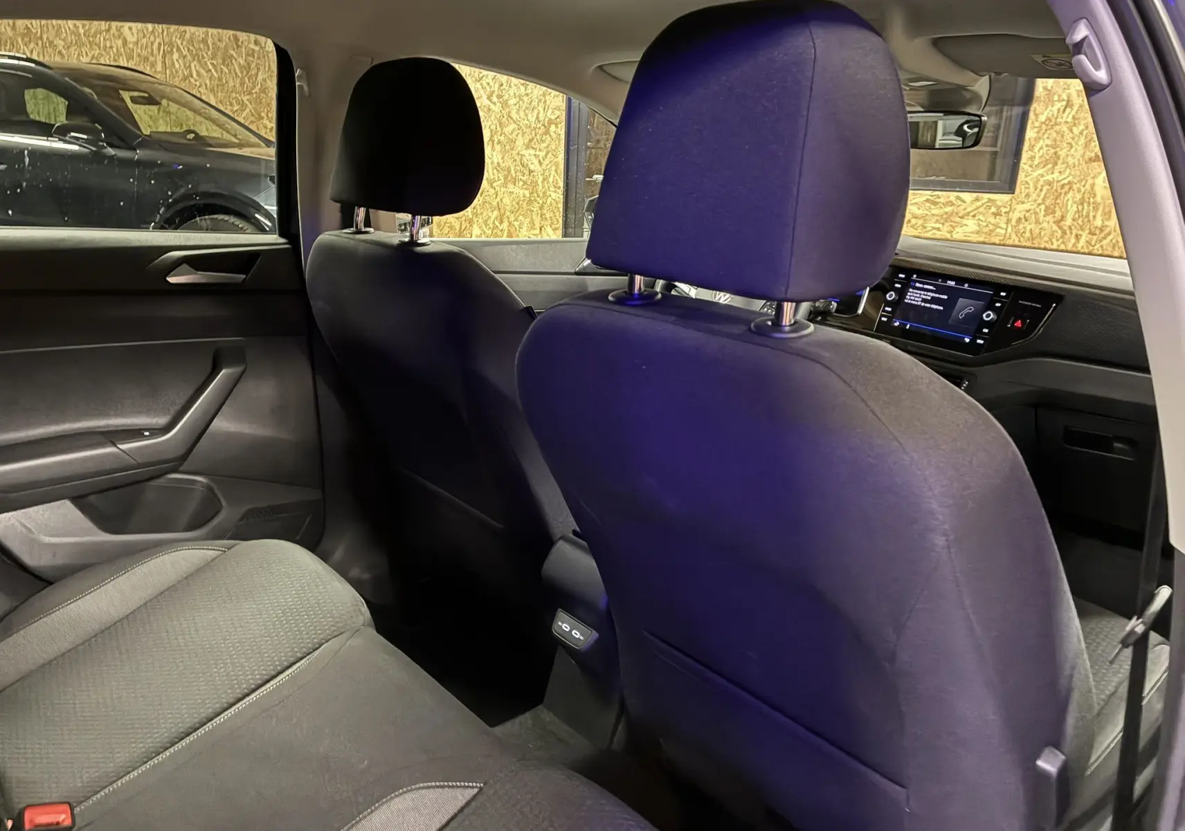 Vue intérieure arrière de la Volkswagen Polo gris 2025, montrant les sièges en tissu noir et le tableau de bord avec écran tactile.