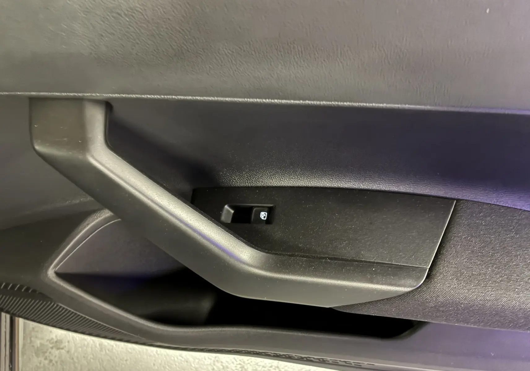 Poignée intérieure de porte côté gauche en plastique noir sur Volkswagen Polo gris 2025, bouton de verrouillage visible.