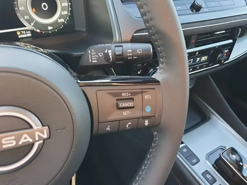 Gros plan sur le volant cuir noir du Nissan Qashqai Hybrid e-POWER 2025 avec commandes multifonctions et tableau de bord digital.
