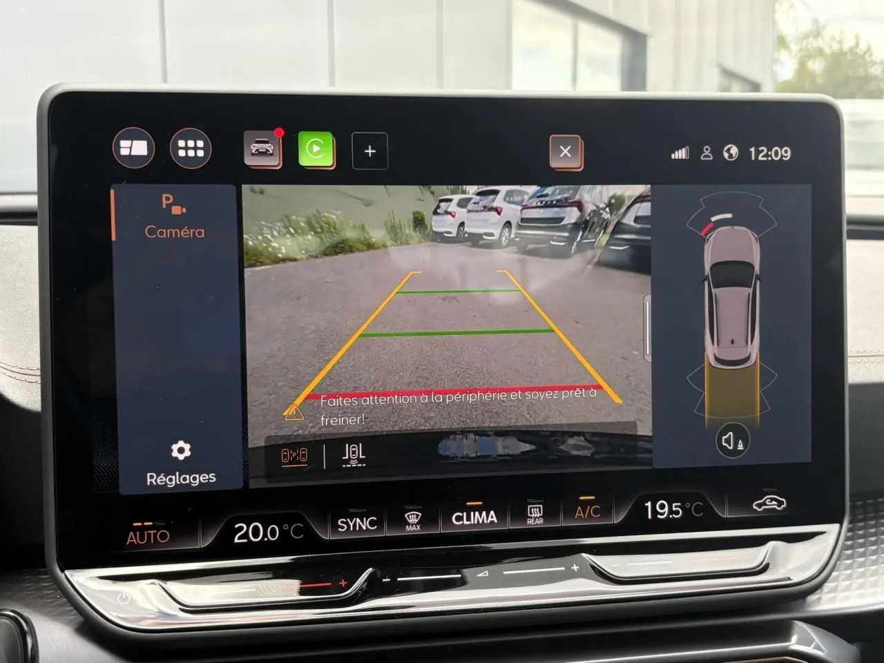 Écran tactile intérieur montrant la caméra de recul avec vue arrière et lignes de guidage jaunes.
