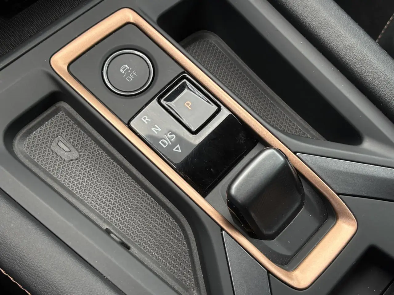 Gros plan sur la console centrale noire et cuivre du CUPRA Formentor avec sélecteur de boîte auto et bouton de contrôle.