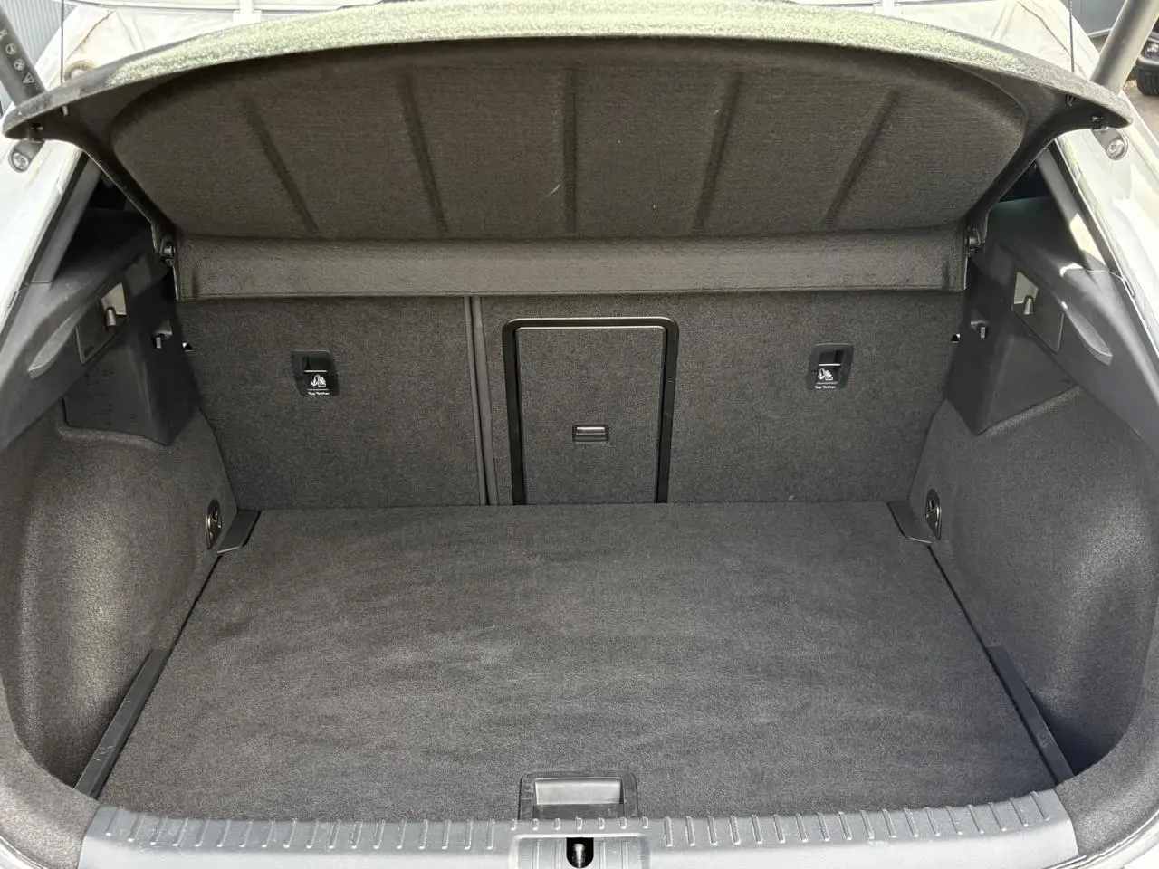 Coffre ouvert vu de l'arrière d'une CUPRA Formentor blanc Neige, intérieur de coffre en tissu gris foncé.