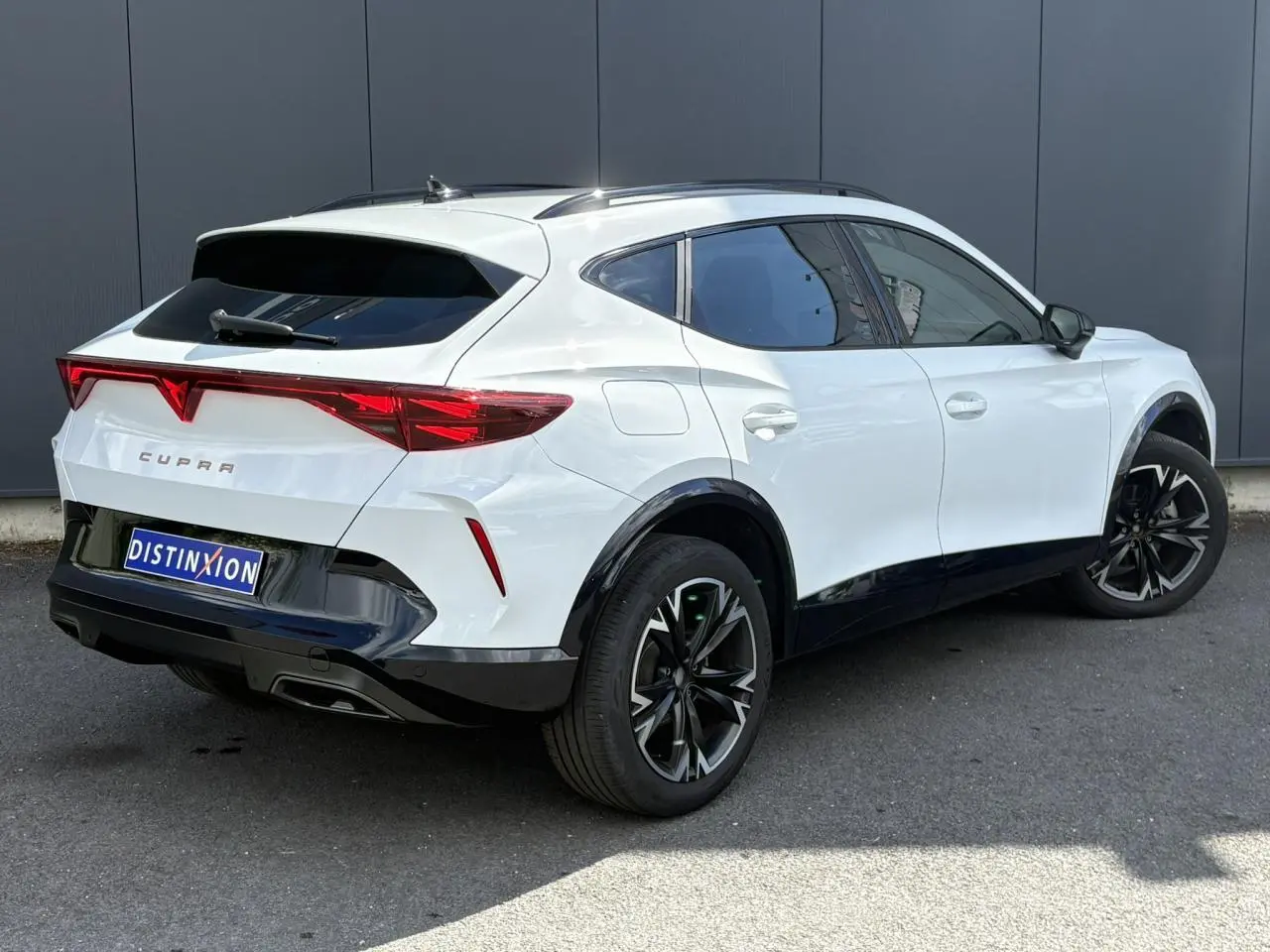 Vue 3/4 arrière droite d'un CUPRA Formentor blanc Neige avec jantes alliage noires et toit noir contrasté.