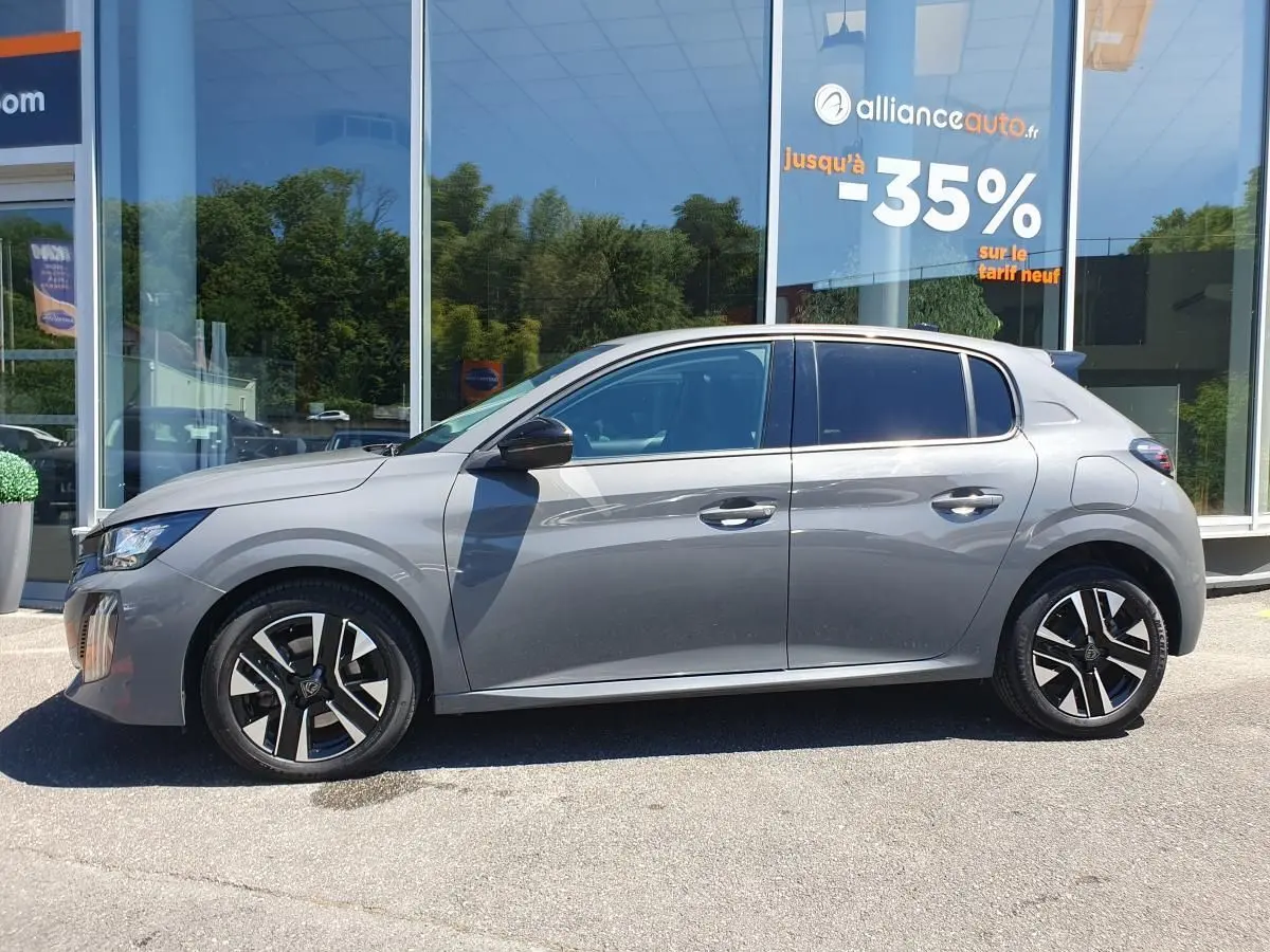Profil côté gauche d'une Peugeot 208 gris Sellenium 2025 avec jantes alliage bi-tons devant une vitrine.
