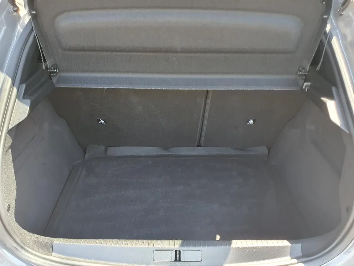 Coffre ouvert de la Peugeot 208 gris Sellenium, vue plongeante montrant l'espace de chargement vide et la moquette noire.
