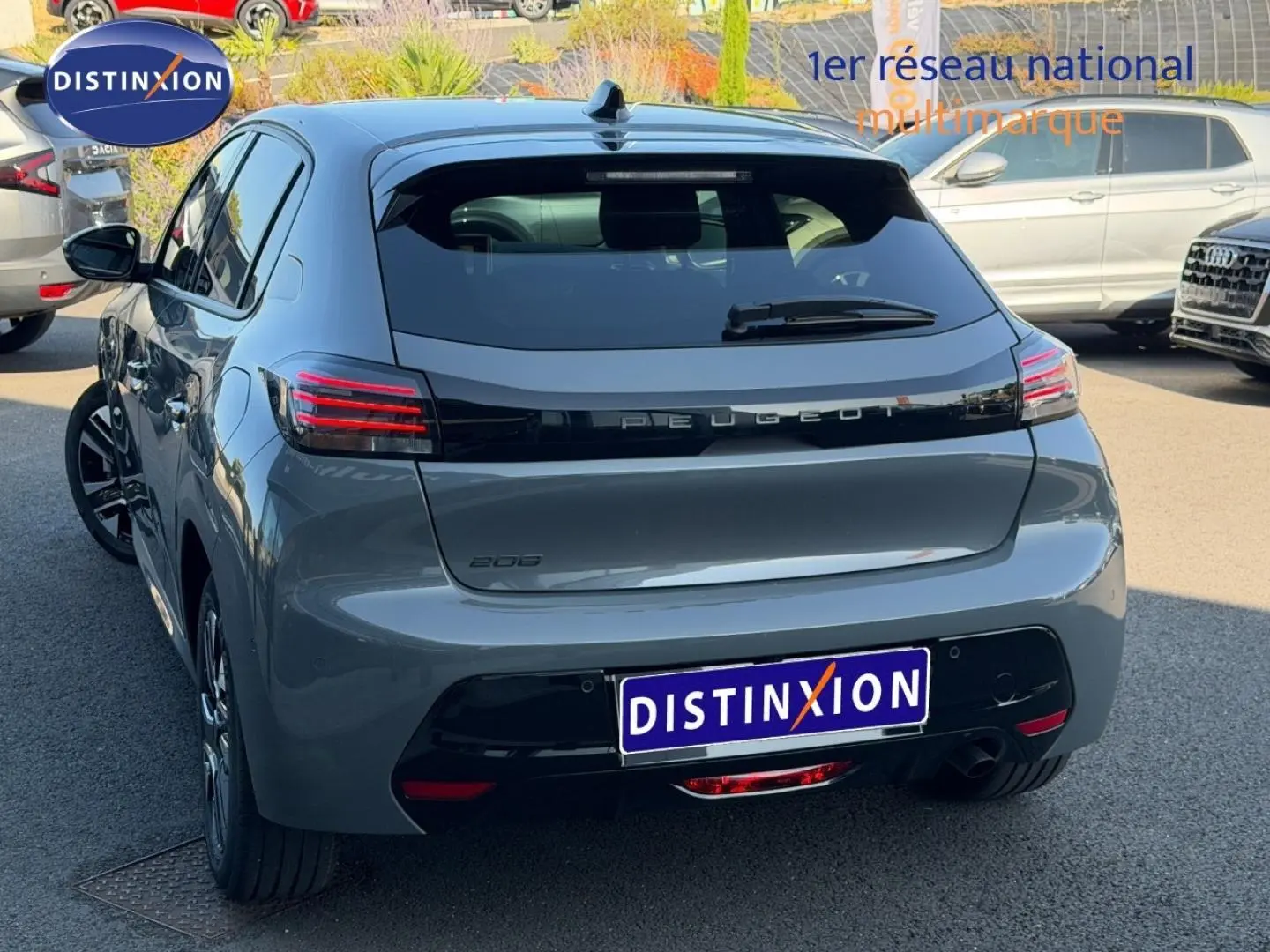 Vue 3/4 arrière droite d'une Peugeot 208 grise avec feux arrière LED et logo distinctif sur le hayon.