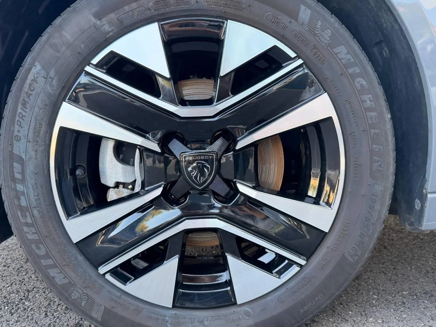Gros plan sur la jante alu bicolore noire et argentée avec logo Peugeot au centre, montée sur pneu Michelin.