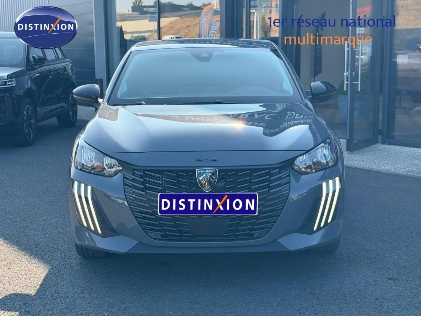 Vue frontale d'une Peugeot 208 grise avec feux LED verticaux allumés, calandre noire et logo lion central.