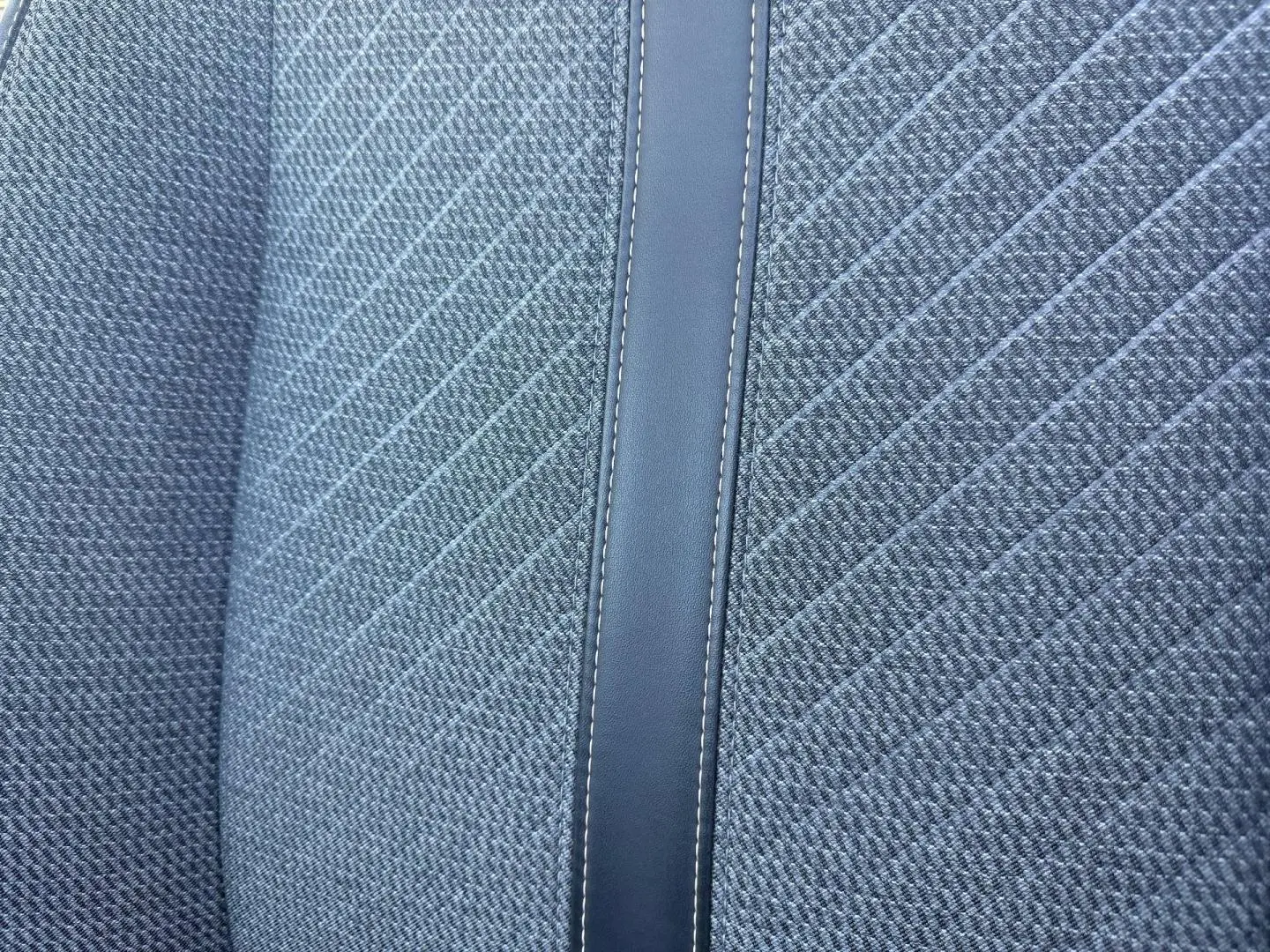 Gros plan sur le tissu gris à motif rayé et la bande centrale en simili cuir du siège avant de la Peugeot 208.