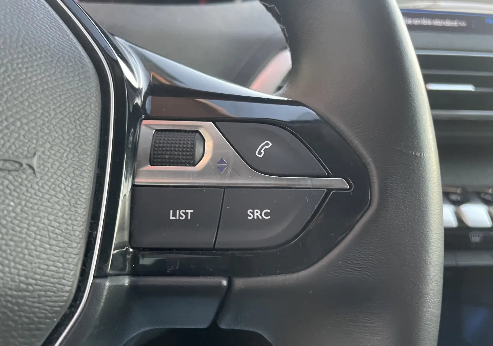 Gros plan sur les commandes gauche du volant du Peugeot 3008 blanc nacré, avec boutons LIST, SRC et téléphone.