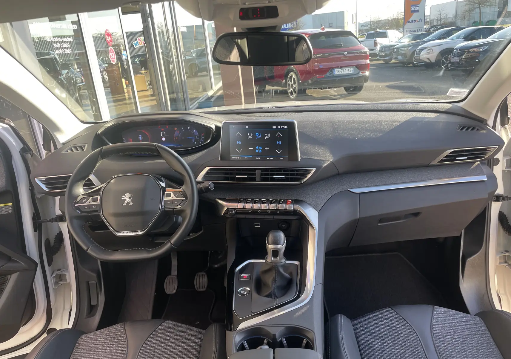 Vue intérieure frontale du Peugeot 3008 blanc nacré 2019, mettant en valeur le tableau de bord moderne et la boîte manuelle.