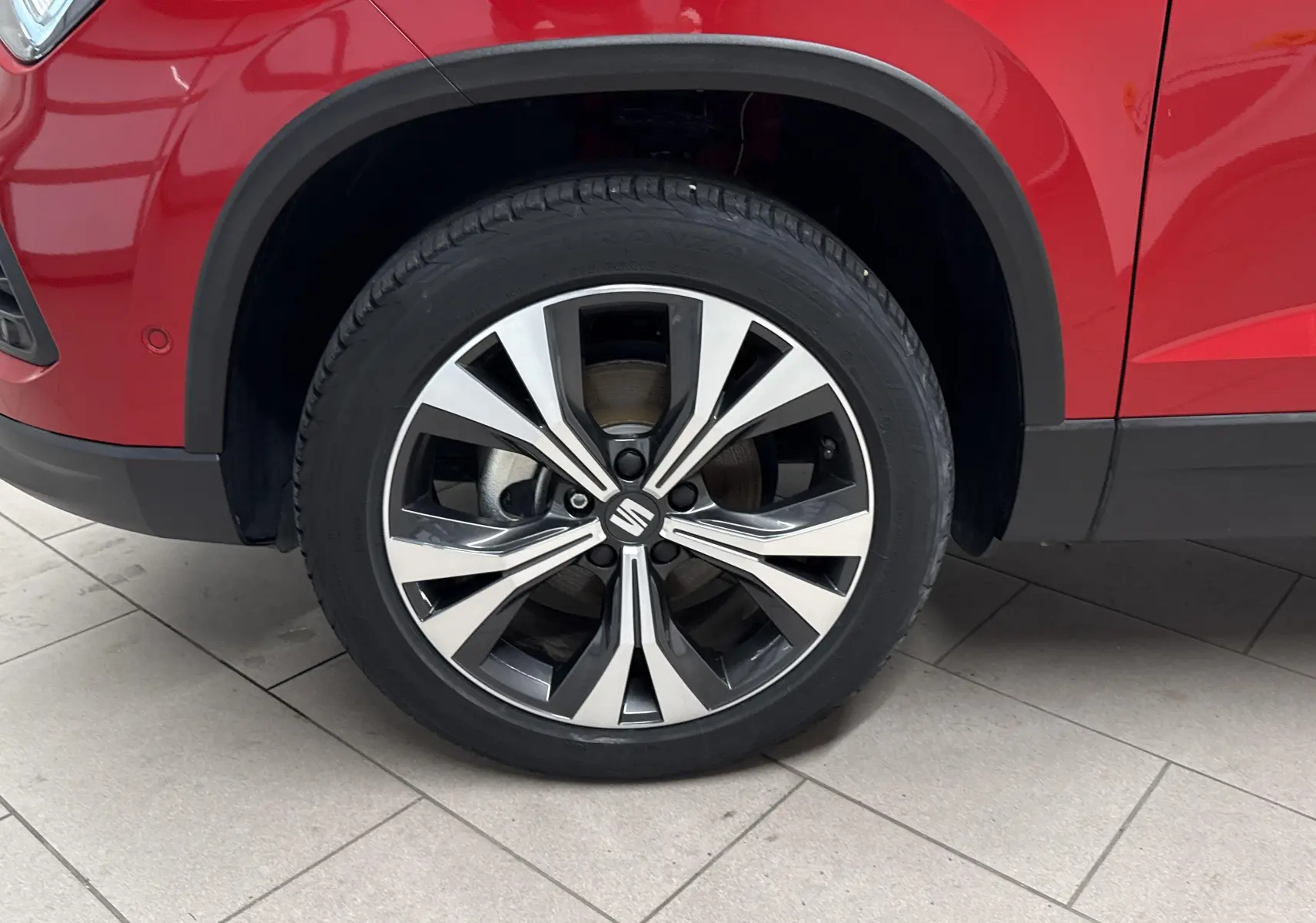 Gros plan sur la roue avant gauche du SEAT Ateca Rouge Velvet, soulignant la jante alliage bicolore moderne.