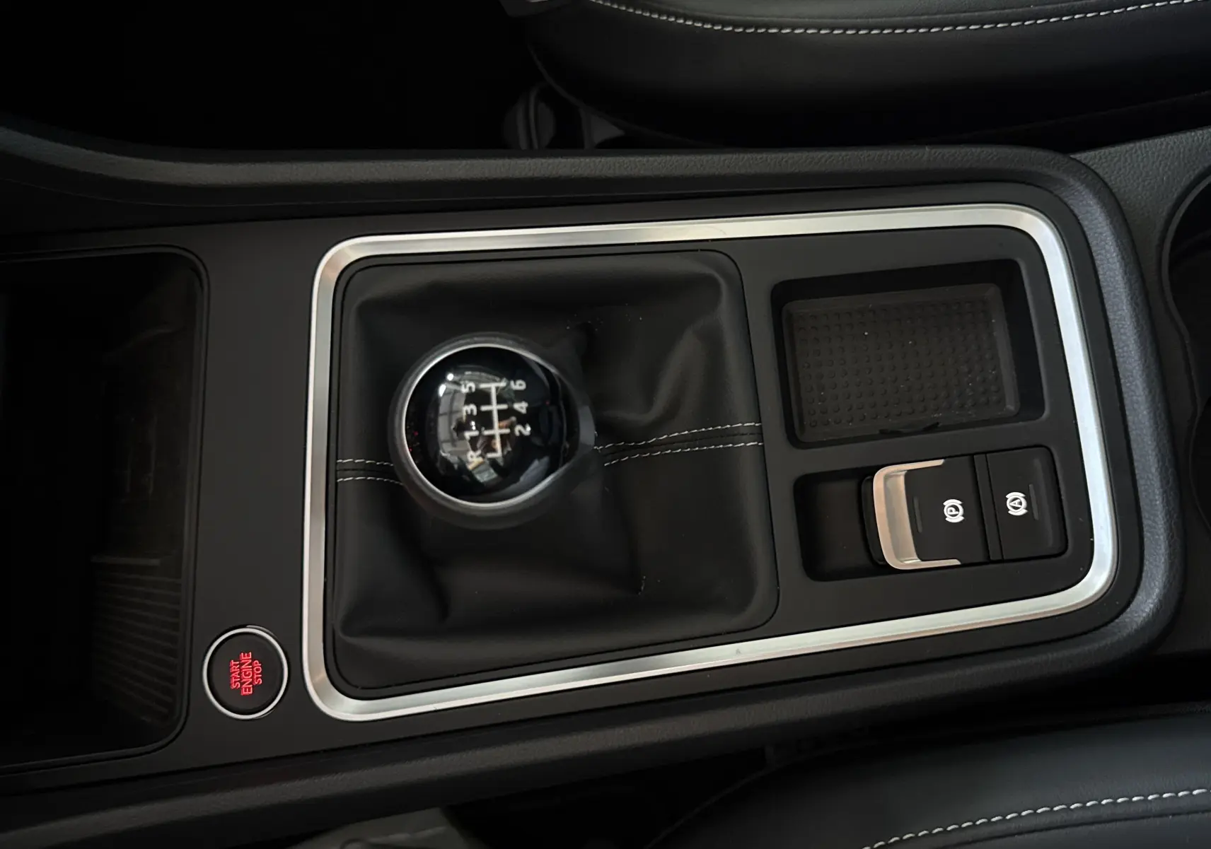 Vue rapprochée de la console centrale du SEAT Ateca 2024 avec levier de vitesse manuel et bouton start/stop rouge.