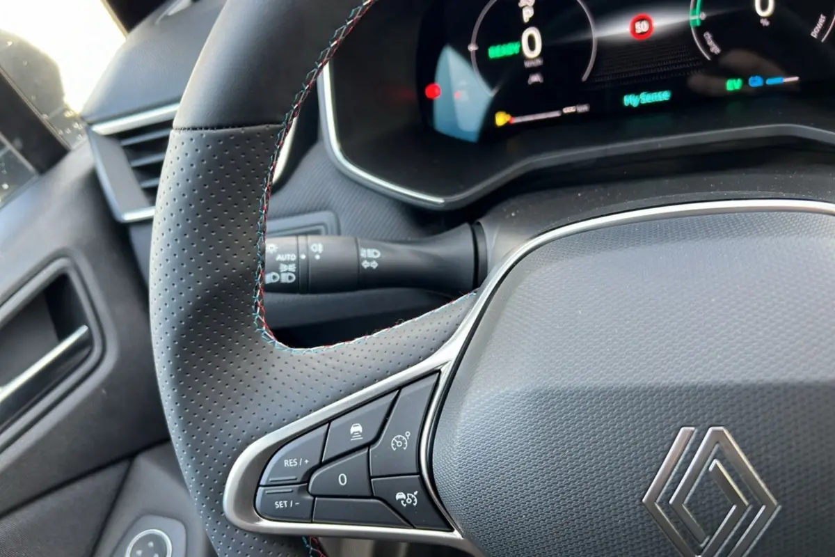 Intérieur de la Renault Clio V E-Tech 145 Esprit Alpine 2025, volant noir perforé avec coutures tricolores et tableau de bord numérique.