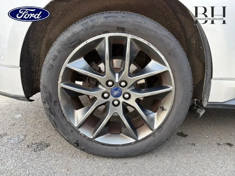 Gros plan sur la jante alliage gris foncé du Ford Edge gris Ingot, montrant le logo Ford au centre.