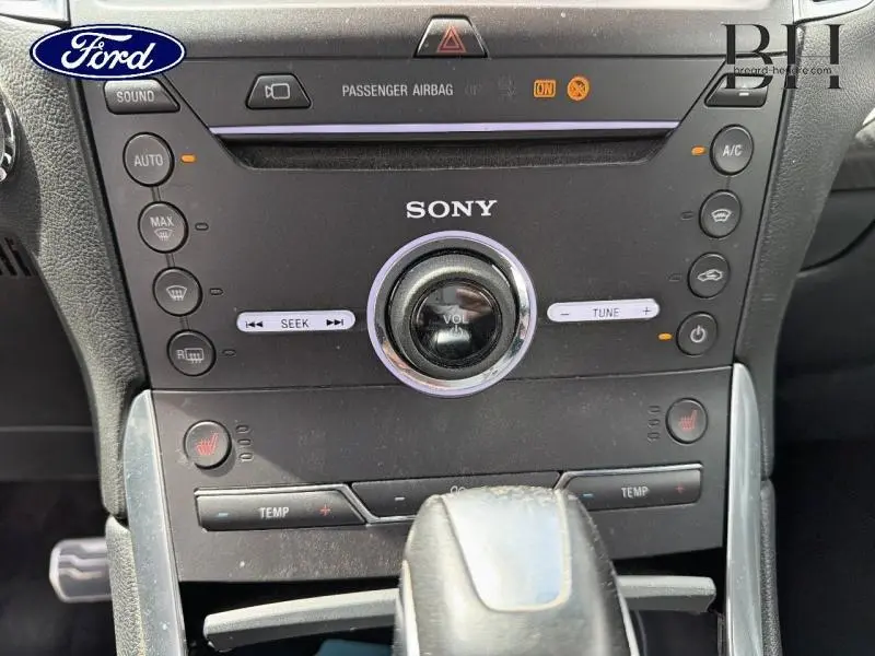 Vue rapprochée du tableau de bord noir du Ford Edge 2016, avec commandes Sony et réglages climatisation visibles.