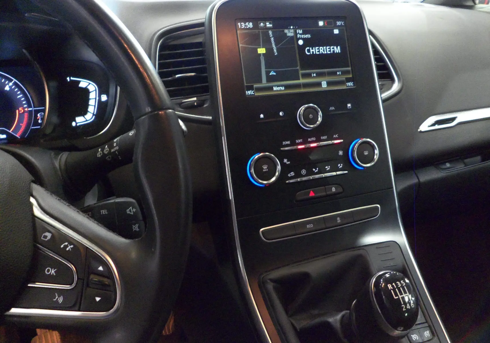 Vue intérieure du tableau de bord et levier de vitesses manuel du Renault Grand Scenic IV blanc glacier, avec écran tactile allumé.