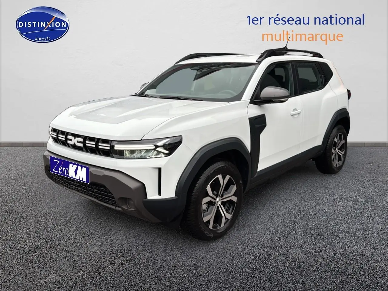 Dacia Duster blanc arctic en 3/4 avant droit avec jantes alu et barres de toit noires.
