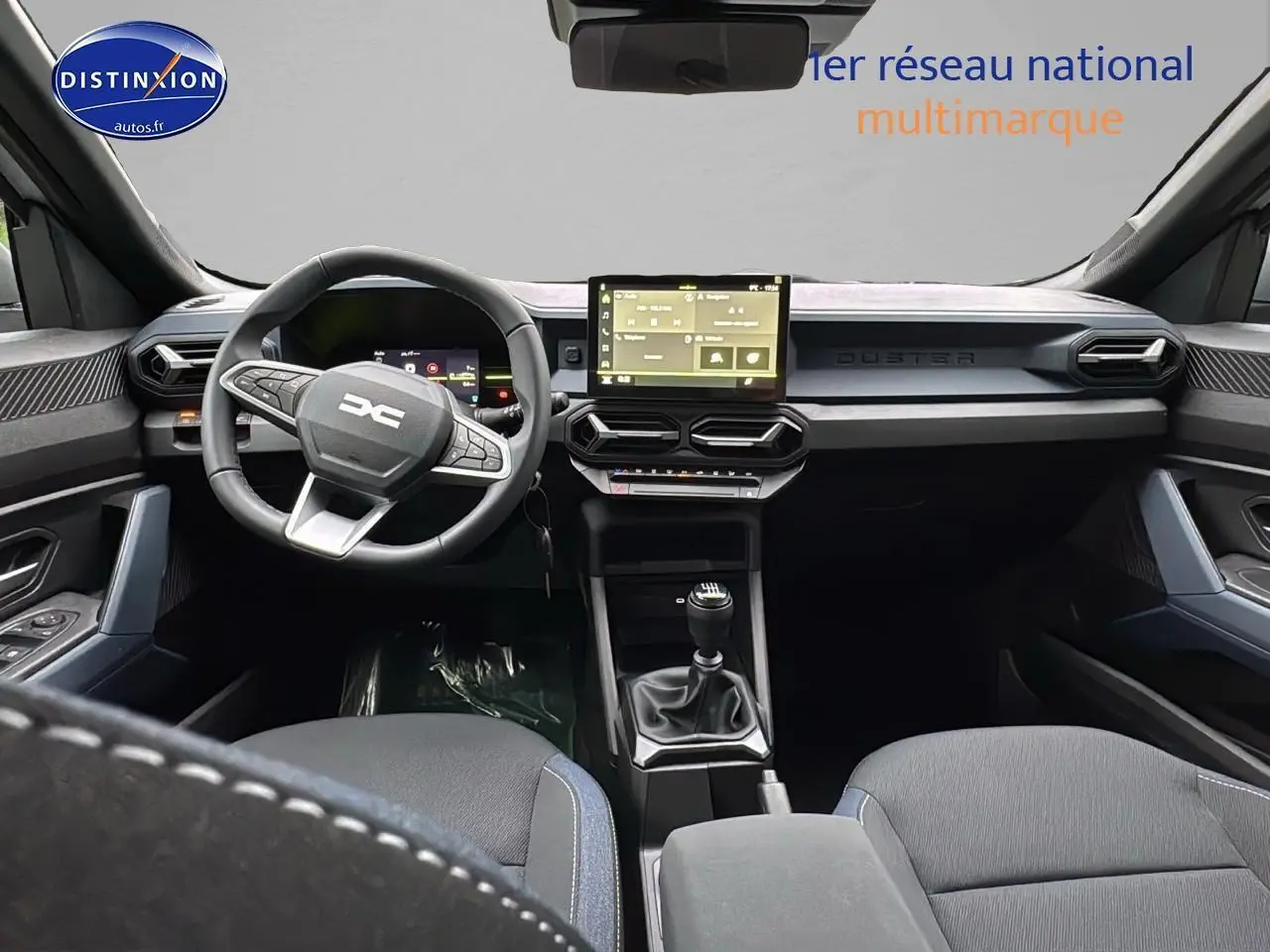 Intérieur du Dacia Duster 2025 vu de face, tableau de bord moderne avec écran tactile et volant multifonction noir.